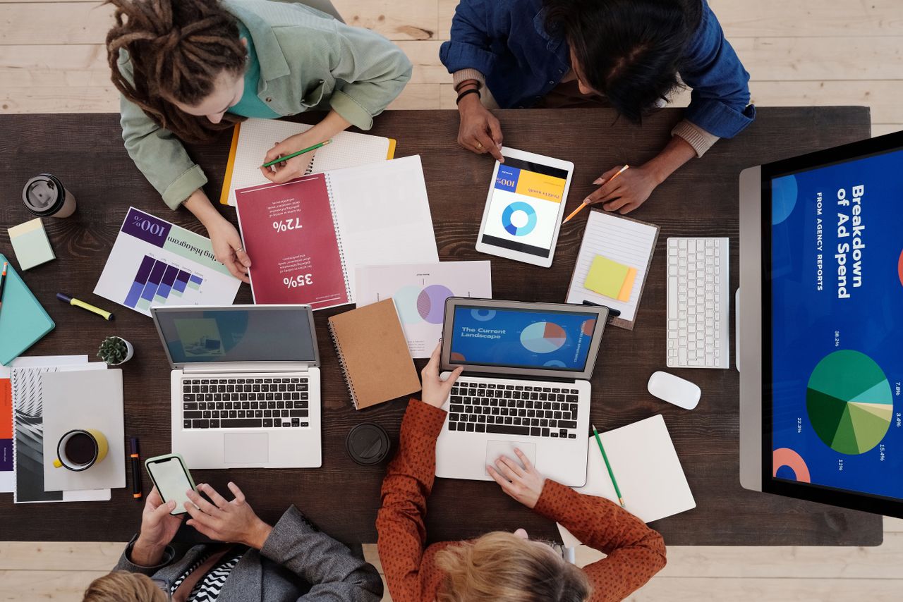 Une équipe diversifiée travaillant ensemble sur des stratégies de marketing digital autour d’un bureau, avec des ordinateurs portables et des tablettes.
